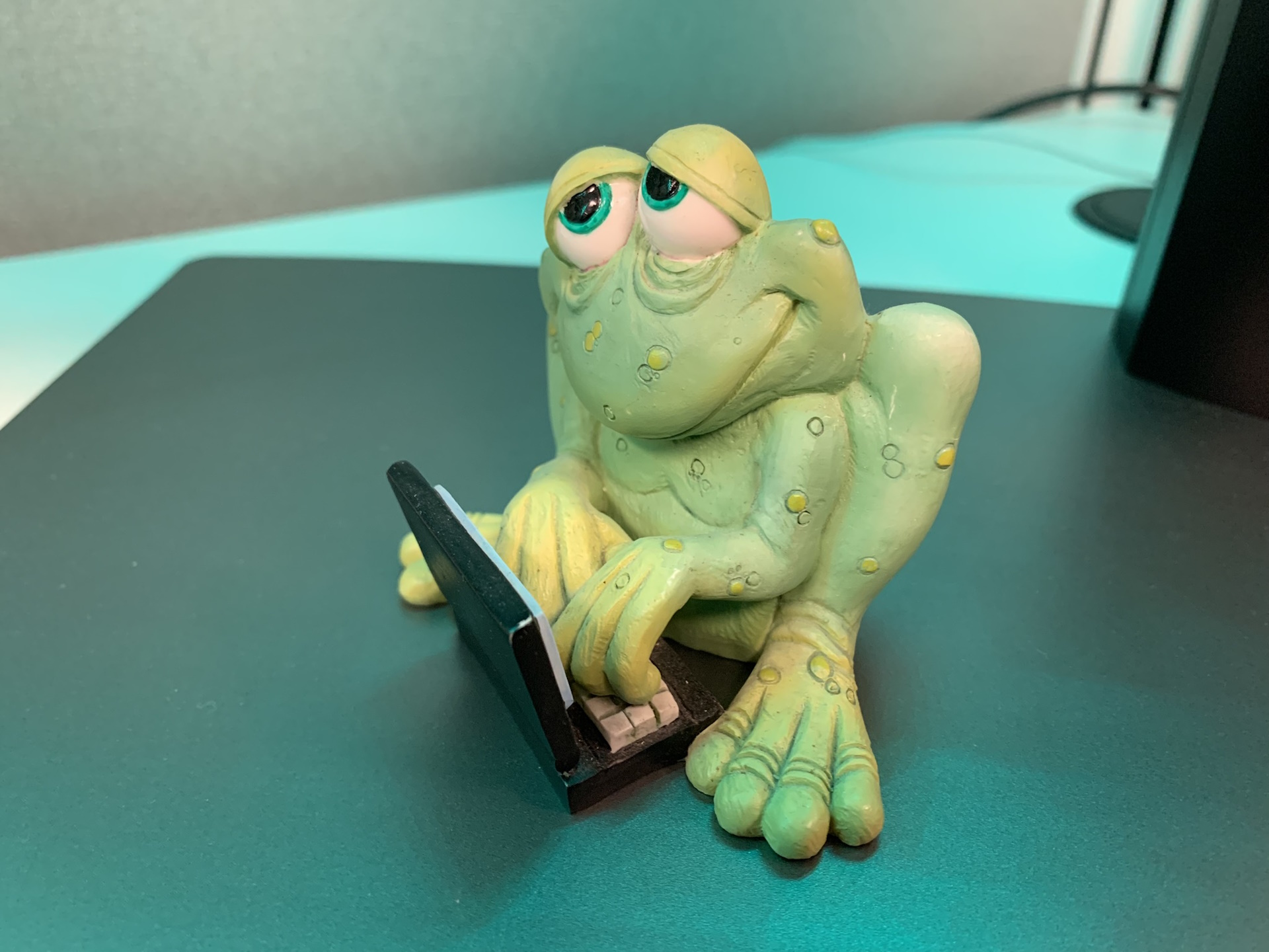 A figurine of a frog using a laptop computer